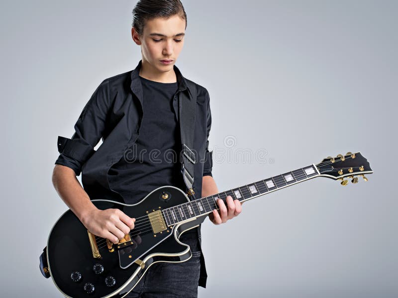 Quinze anos de guitarrista idoso com uma guitarra elétrica preta O músico adolescente guarda a guitarra imagens de stock Quinze anos de guitarrista idoso com uma guitarra elétrica preta O músico adolescente guarda a guitarra imagens de stock