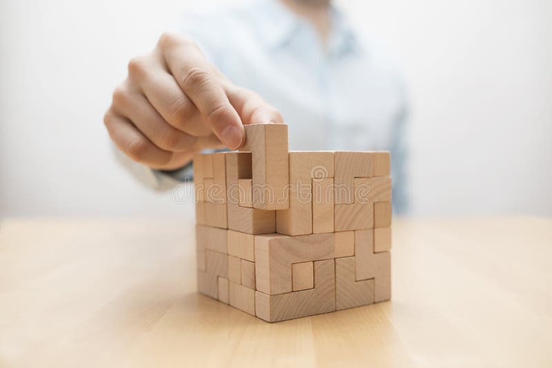 Man`s hand adding the last missing wooden block into place. Business success concept. Man`s hand adding the last missing wooden block into place. Business success concept.