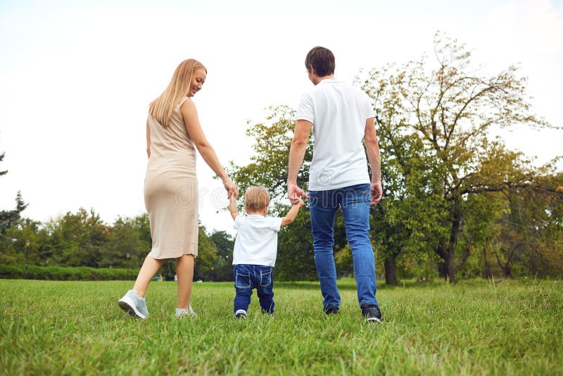R?ckseitige Ansicht Familie mit einem Kind geht in den Park stockfoto R?ckseitige Ansicht Familie mit einem Kind geht in den Park stockfoto