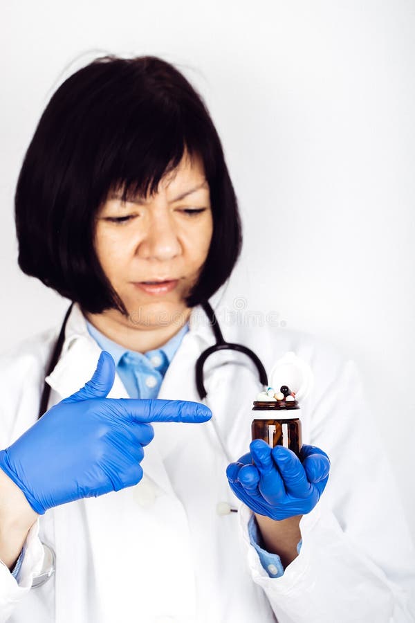 R?ki w medycznych r?kawiczkach trzyma szklan? butelk? z wiele r??nymi pigu?kami obrazy stock R?ki w medycznych r?kawiczkach trzyma szklan? butelk? z wiele r??nymi pigu?kami obrazy stock