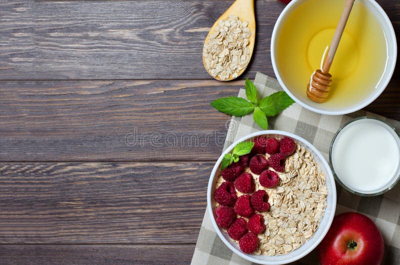 R Oatmeal με το σμέουρο Ξύλινο κουτάλι με τα δημητριακά, γάλα σε ένα γυαλί, μήλο Καφετί ξύλινο υπόβαθρο E στοκ εικόνες με δικαίωμα ελεύθερης χρήσης