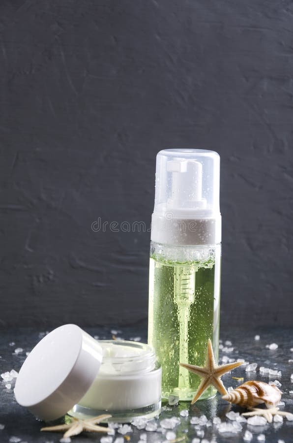 r Бутылка moisturizing продукта красоты, стеклянный опарник moisturizing сливк, соль моря и раковины на сером поверхностном aga стоковое фото rf r Бутылка moisturizing продукта красоты, стеклянный опарник moisturizing сливк, соль моря и раковины на сером поверхностном aga стоковое фото rf