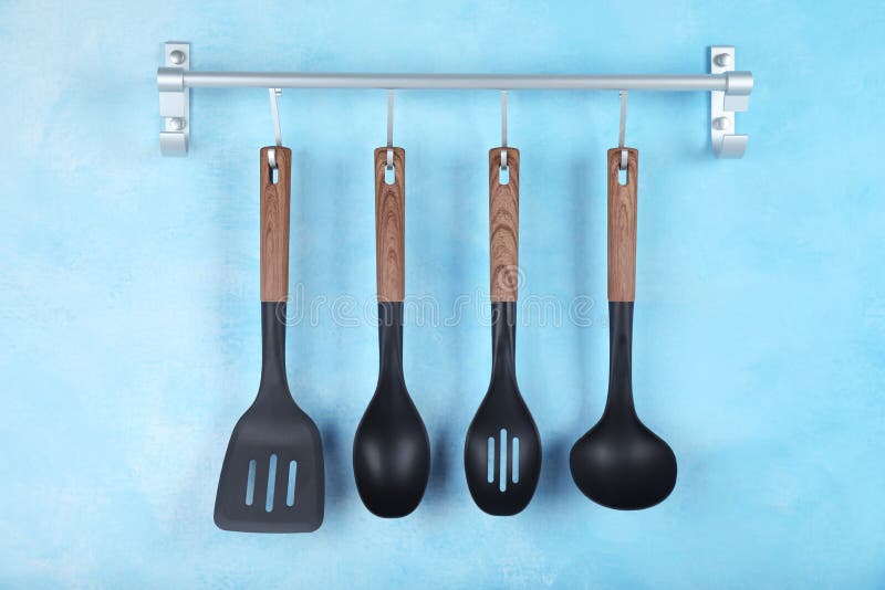 Rack with Kitchen Utensils Hanging on Light Blue Wall Stock Photo