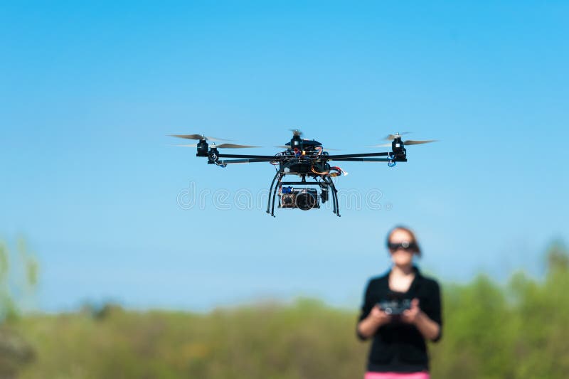 Airborne radio controlled helicopter with woman controller in background. Airborne radio controlled helicopter with woman controller in background.