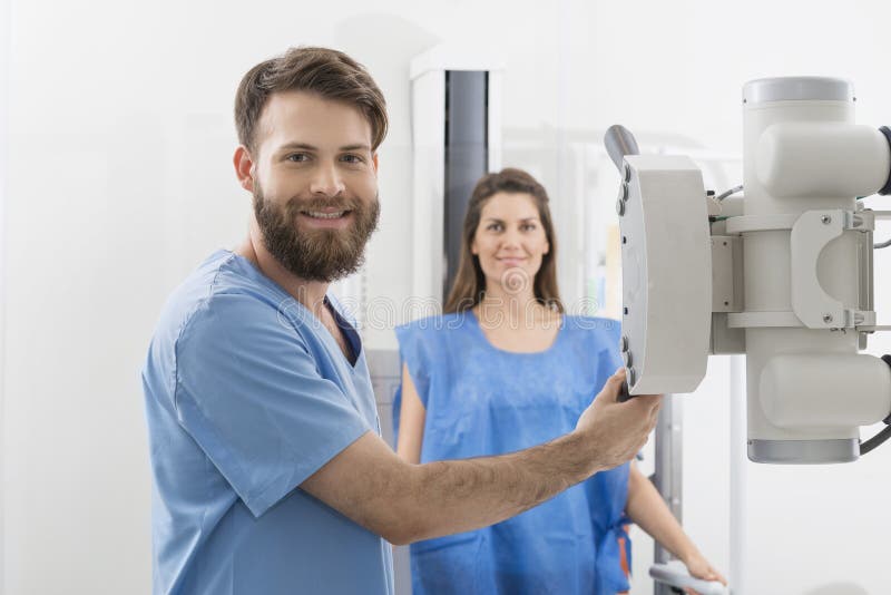 Radiologe-Adjusting-Röntgenmaschine über weiblichem Patienten in Hospi lizenzfreie stockfotografie
