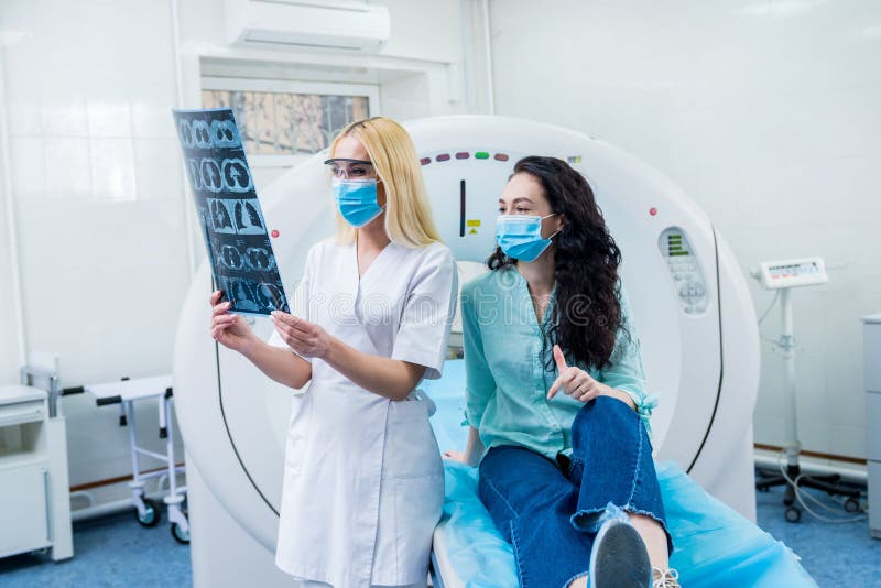 Radiologe mit Portieren Schutzmasken eines weiblichen Patienten einen ct-Scan Prüfung.