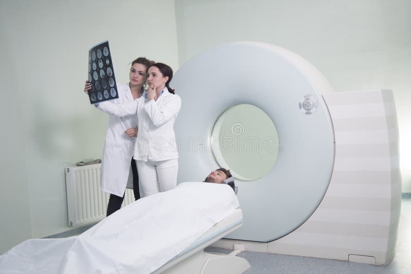 Radiologic technician and Patient being scanned and diagnosed on CT scanner in hospital. Radiologic technician and Patient being scanned and diagnosed on CT scanner in hospital.