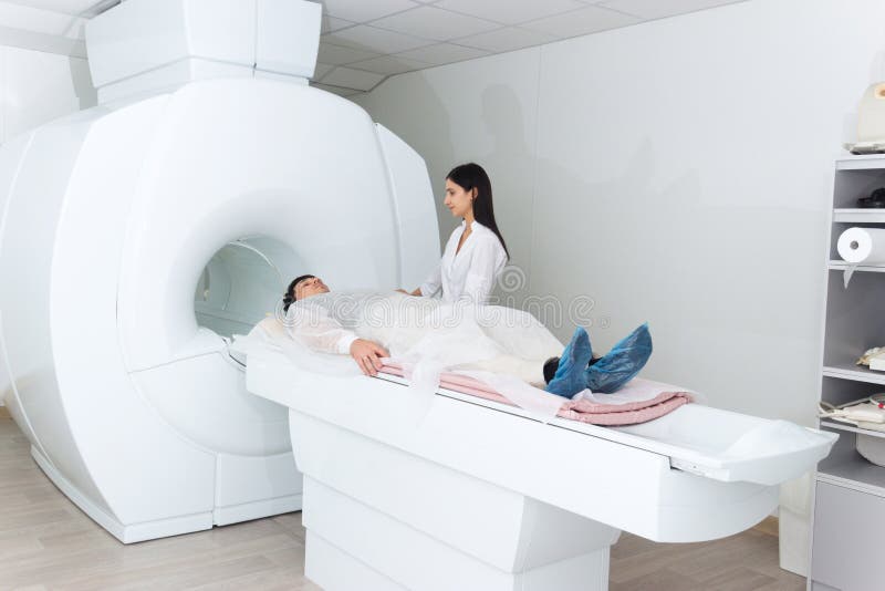 Radiologic technician and men patient lying on a CT Scan bed. preparing for MRI magnetic resonance imaging in a hospital. Radiologic technician and men patient lying on a CT Scan bed. preparing for MRI magnetic resonance imaging in a hospital.