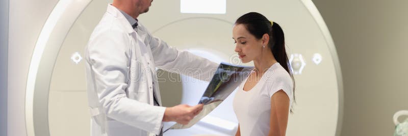 Radiologue regarde les résultats de l'irm et met sa main sur l'épaule d'un patient triste. image stock