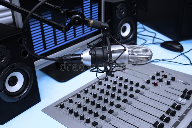 A mic in front of the control panel and screen in broadcasting studio. A mic in front of the control panel and screen in broadcasting studio
