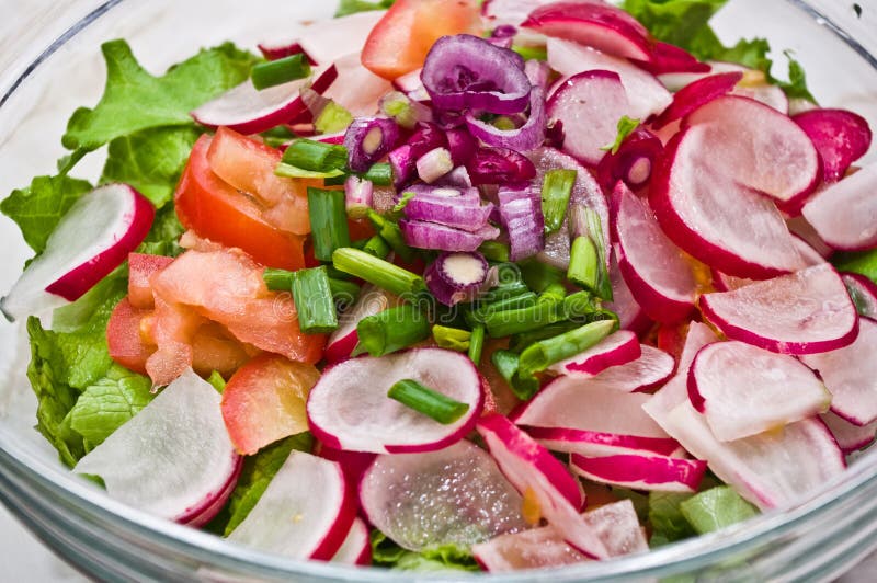 Radish Salad. Ingredients for a Radish Salad in a glass bowl, just before being mixed together (radishes, lettuce, tomatoes, red onion, green onion, olive oil stock photo Radish Salad. Ingredients for a Radish Salad in a glass bowl, just before being mixed together (radishes, lettuce, tomatoes, red onion, green onion, olive oil stock photo