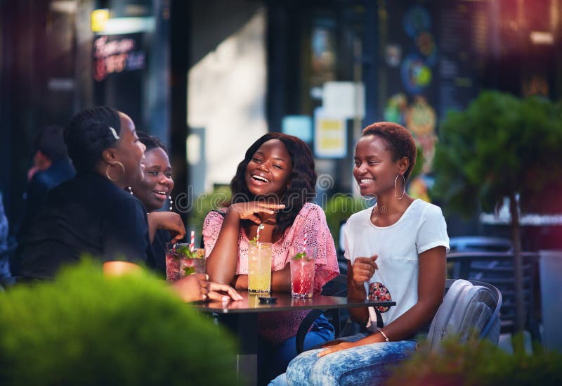 Happy African American Women, friends are sitting together at the outdoor restaurant at summer day. Happy African American Women, friends are sitting together at the outdoor restaurant at summer day