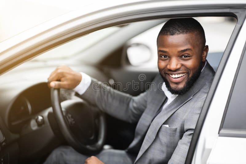 Radosny, udany czarny biznesmen patrzący przez okno samochodu