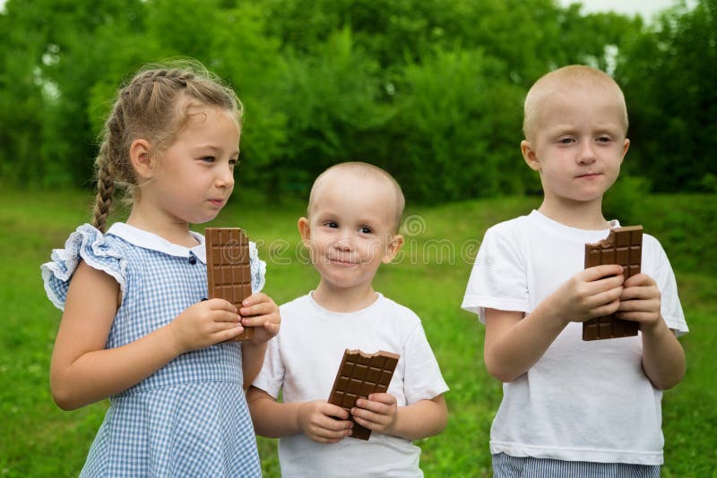 Radośni dzieciaki je czekoladę outdoors zdjęcie stock