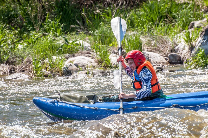 Rafting, kayaking. Young girl sailing on a rubber inflatable boat in a stormy stream of water. Water splashes close-up. royalty free stock image Rafting, kayaking. Young girl sailing on a rubber inflatable boat in a stormy stream of water. Water splashes close-up. royalty free stock image