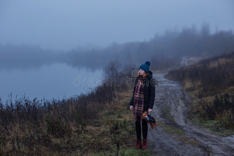 Ragazza adolescente con orsacchiotto su una strada di campagna al lago nebbioso Concetto di adolescenza e problemi dell'adolescen fotografie stock libere da diritti Ragazza adolescente con orsacchiotto su una strada di campagna al lago nebbioso Concetto di adolescenza e problemi dell'adolescen fotografie stock libere da diritti