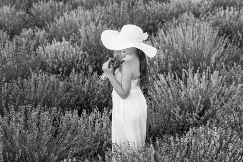 Ragazza adolescente con un fiore di lavanda in piedi sul campo. adolescente con lavanda in mano un bouquet di fiori. ragazza adole immagini stock