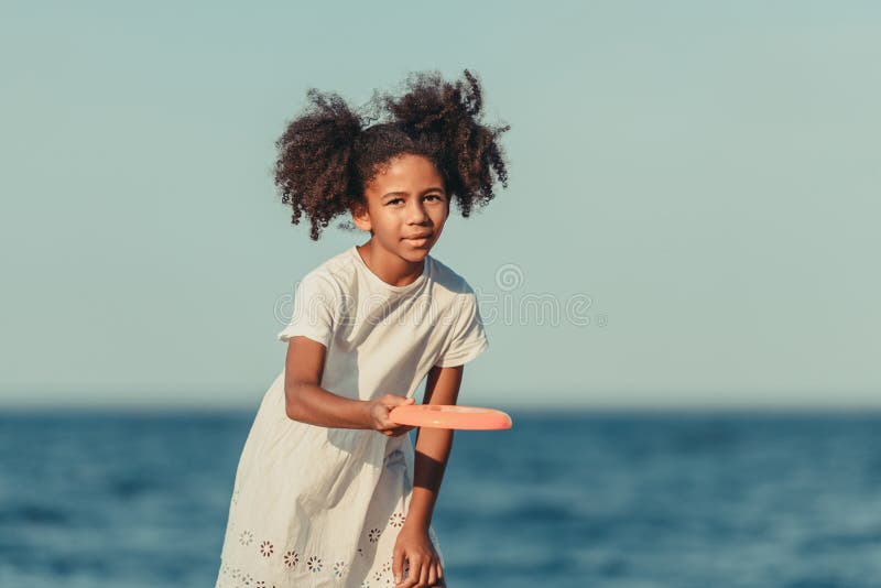 ragazza afroamericana sveglia che gioca con il disco di volo e che esamina macchina fotografica immagine stock ragazza afroamericana sveglia che gioca con il disco di volo e che esamina macchina fotografica immagine stock