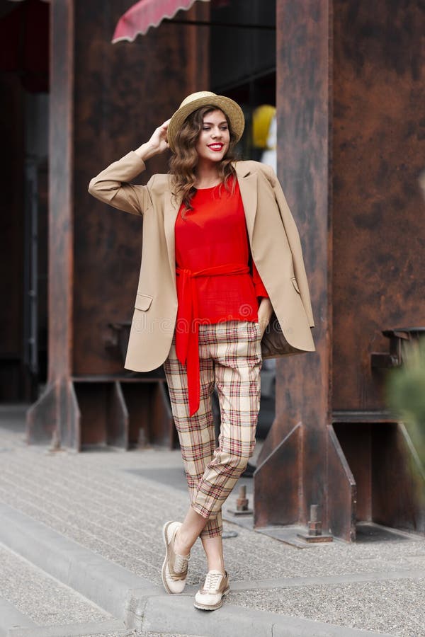 Ragazza alla moda in abbigliamento casual d'avanguardia vestito nelle pose del cappello e di un rivestimento nella via un giorno immagini stock Ragazza alla moda in abbigliamento casual d'avanguardia vestito nelle pose del cappello e di un rivestimento nella via un giorno immagini stock