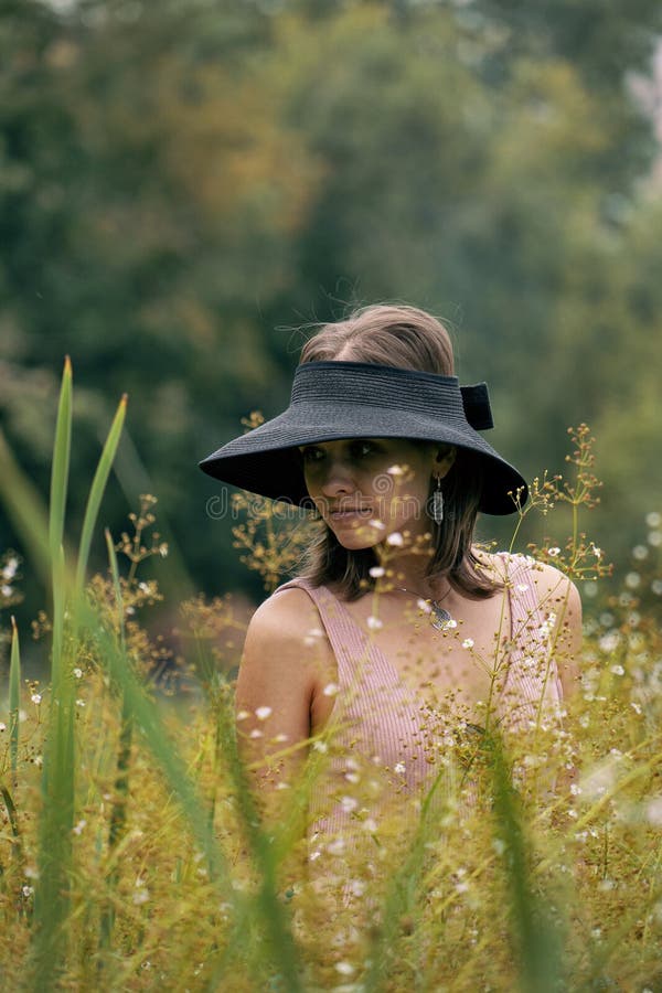 Ragazza alla moda che posa ai wildflowers Ritratto della donna calma che si rilassa fra l'erba fotografia stock Ragazza alla moda che posa ai wildflowers Ritratto della donna calma che si rilassa fra l'erba fotografia stock