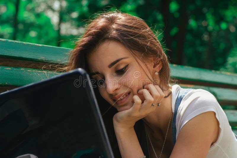 Ragazza allegra del ritratto del primo piano una giovane con un computer portatile fotografia stock Ragazza allegra del ritratto del primo piano una giovane con un computer portatile fotografia stock