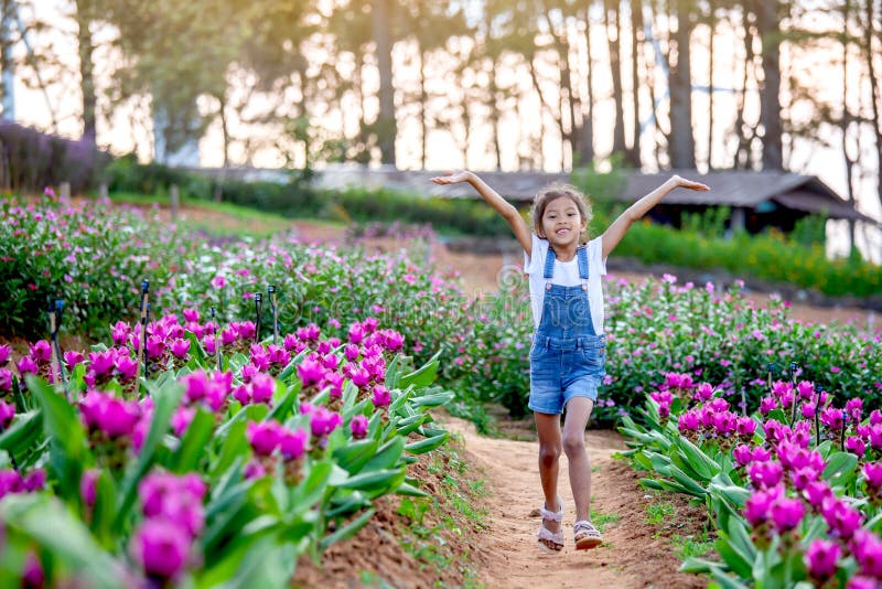 Ragazza asiatica sveglia del bambino alzare le loro armi e funzionare nel giardino floreale immagini stock libere da diritti Ragazza asiatica sveglia del bambino alzare le loro armi e funzionare nel giardino floreale immagini stock libere da diritti