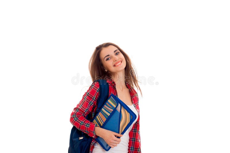 Ragazza astuta alla moda felice dello studente con lo zaino sulle sue spalle e cartelle per i taccuini in mani che posano e che s fotografia stock Ragazza astuta alla moda felice dello studente con lo zaino sulle sue spalle e cartelle per i taccuini in mani che posano e che s fotografia stock