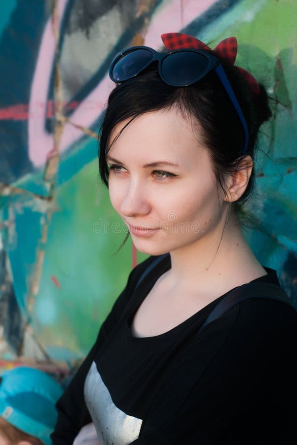 Ragazza attraente in bomber che posa contro il contesto delle pareti ruvide dipinte nei disegni dei graffiti fotografie stock libere da diritti Ragazza attraente in bomber che posa contro il contesto delle pareti ruvide dipinte nei disegni dei graffiti fotografie stock libere da diritti