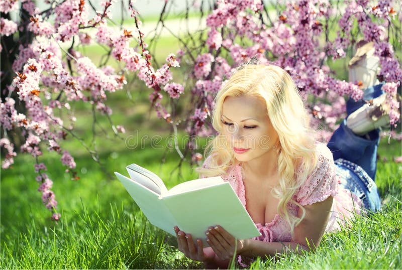 Ragazza bionda che legge il libro sotto Cherry Blossom fotografia stock Ragazza bionda che legge il libro sotto Cherry Blossom fotografia stock