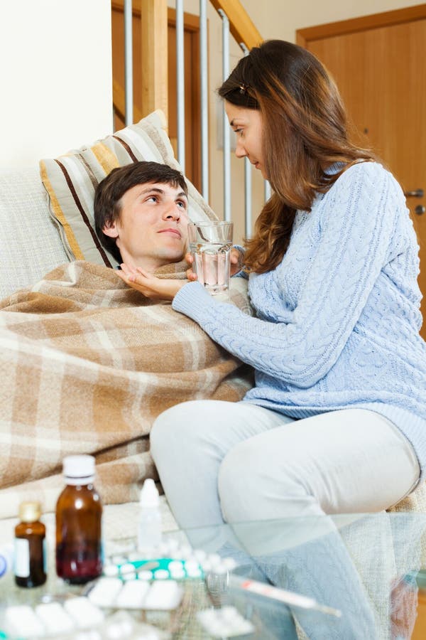 Ragazza che dà medicinale al marito indisposto fotografie stock libere da diritti Ragazza che dà medicinale al marito indisposto fotografie stock libere da diritti