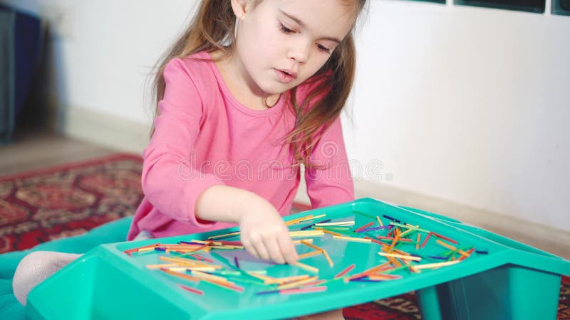Ragazza che gioca con i bastoni di legno variopinti sul pavimento stock footage