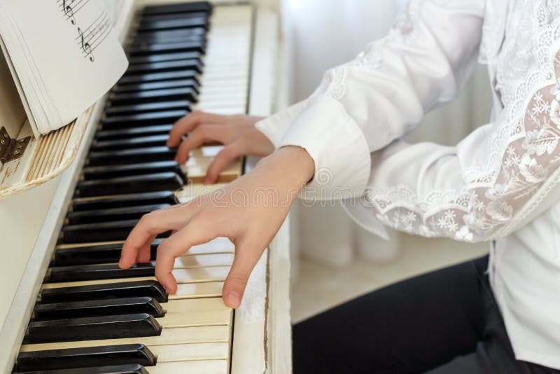 Ragazza che gioca sul piano bianco Mani di una ragazza che preme i tasti del piano immagini stock libere da diritti Ragazza che gioca sul piano bianco Mani di una ragazza che preme i tasti del piano immagini stock libere da diritti