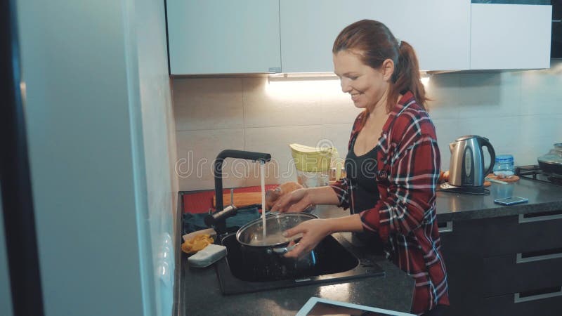 Ragazza che lava i piatti nel tagliere della cucina Cuochi della donna nella cucina la ragazza lava un coltello sullo stile di vi