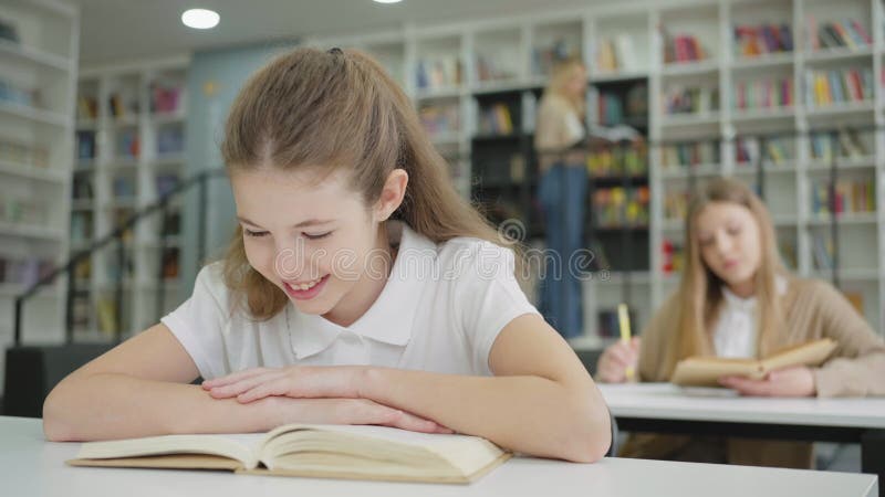 Ragazza che legge un libro divertente in classe e ride