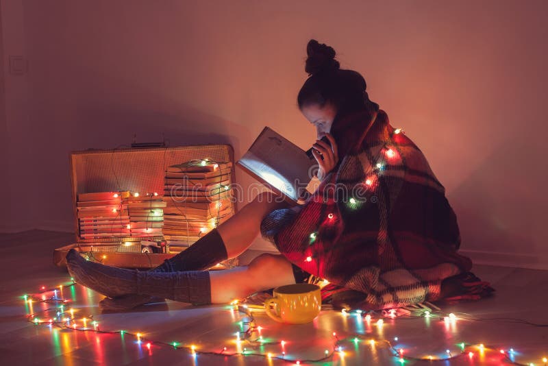 Ragazza che legge un libro sotto la coperta a casa immagini stock Ragazza che legge un libro sotto la coperta a casa immagini stock