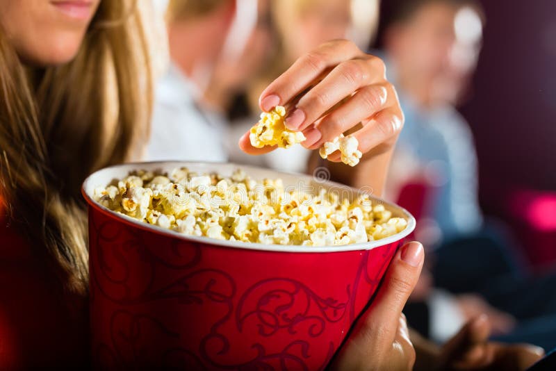 Ragazza che mangia popcorn in cinematografo o nel cinema