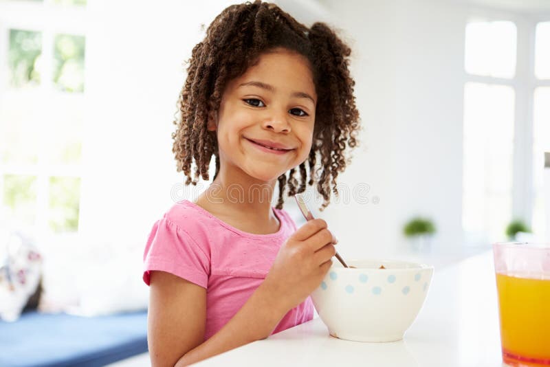 Ragazza che mangia prima colazione in cucina fotografia stock libera da diritti Ragazza che mangia prima colazione in cucina fotografia stock libera da diritti