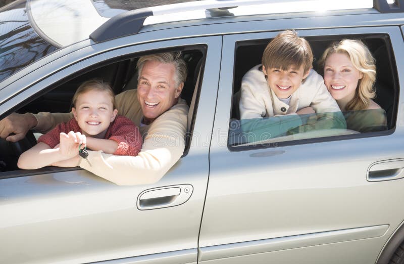 Ragazza che mostra le chiavi dell'automobile mentre sedendosi con la famiglia in automobile fotografia stock libera da diritti Ragazza che mostra le chiavi dell'automobile mentre sedendosi con la famiglia in automobile fotografia stock libera da diritti
