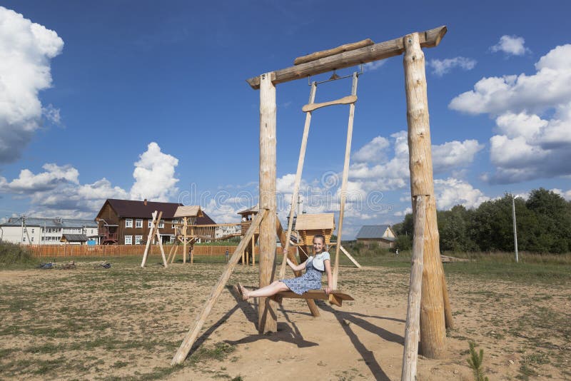 Ragazza che oscilla sull'le oscillazioni di legno enormi al parco fotografia stock Ragazza che oscilla sull'le oscillazioni di legno enormi al parco fotografia stock