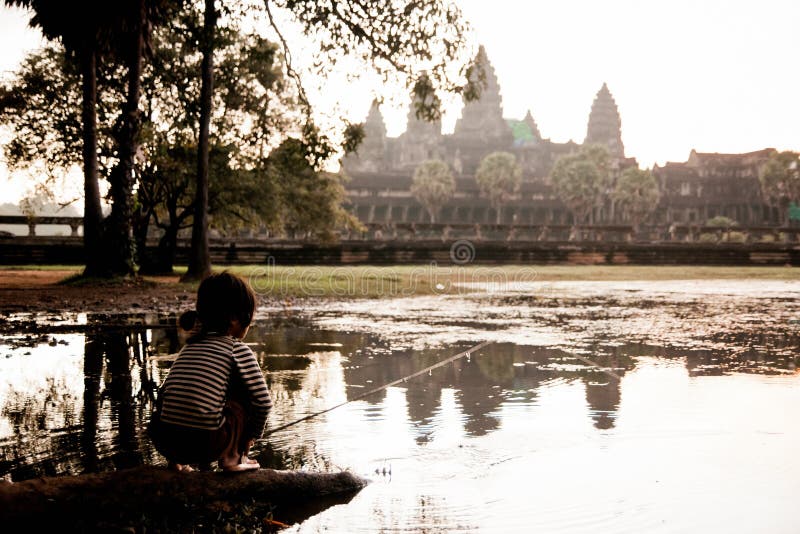 Ragazza che pesca nel lago di Angkor Wat, antica città cambogiana nascosta nella foresta molto visitata dai turisti fotografia stock libera da diritti Ragazza che pesca nel lago di Angkor Wat, antica città cambogiana nascosta nella foresta molto visitata dai turisti fotografia stock libera da diritti
