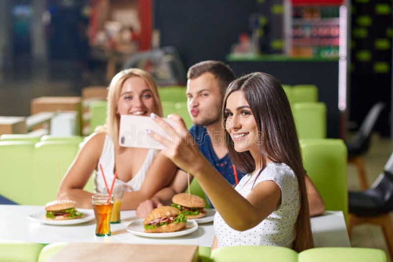 Ragazza che prende selfie insieme agli amici felici immagine stock Ragazza che prende selfie insieme agli amici felici immagine stock