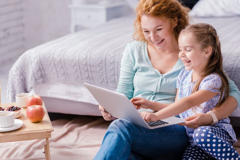 Ragazza che si siede davanti al computer portatile con sua nonna immagine stock libera da diritti Ragazza che si siede davanti al computer portatile con sua nonna immagine stock libera da diritti