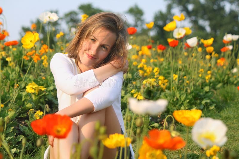 Ragazza che si siede intorno ai papaveri nella sera in primavera fotografie stock libere da diritti Ragazza che si siede intorno ai papaveri nella sera in primavera fotografie stock libere da diritti