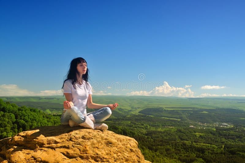 Ragazza che si siede nella posizione di loto sulla montagna fotografia stock Ragazza che si siede nella posizione di loto sulla montagna fotografia stock