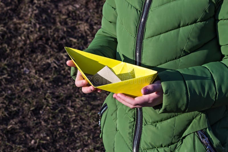 Ragazza che tiene una barca di carta gialla, crogiolo di carta di primo piano, fotografia stock Ragazza che tiene una barca di carta gialla, crogiolo di carta di primo piano, fotografia stock