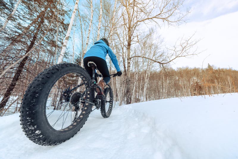 Ragazza ciclista ciclistica ciclistica in bicicletta mentre corre sulle tracce di neve d'inverno. sport all'aperto nel paesaggio n