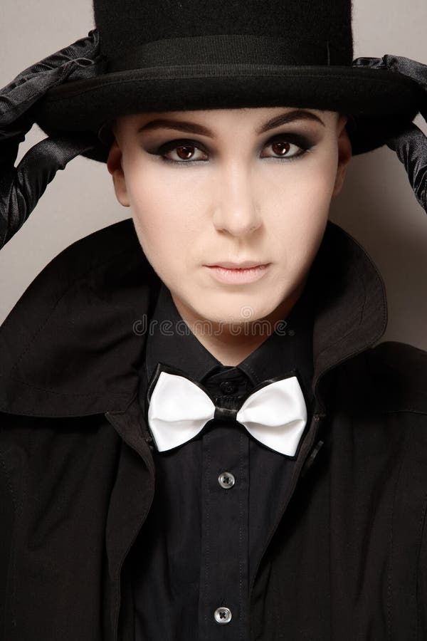 Portrait of skinhead girl with dark makeup holding black hat. Portrait of skinhead girl with dark makeup holding black hat