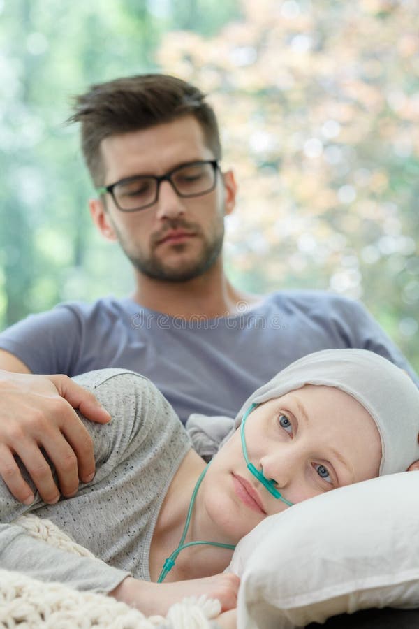 Girl with nasal cannula resting on couch supported by boyfriend. Girl with nasal cannula resting on couch supported by boyfriend