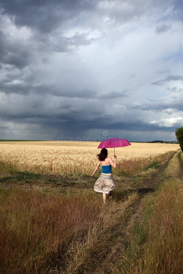 Girl with umbrella running at field in storm, Photo # 1. Girl with umbrella running at field in storm, Photo # 1