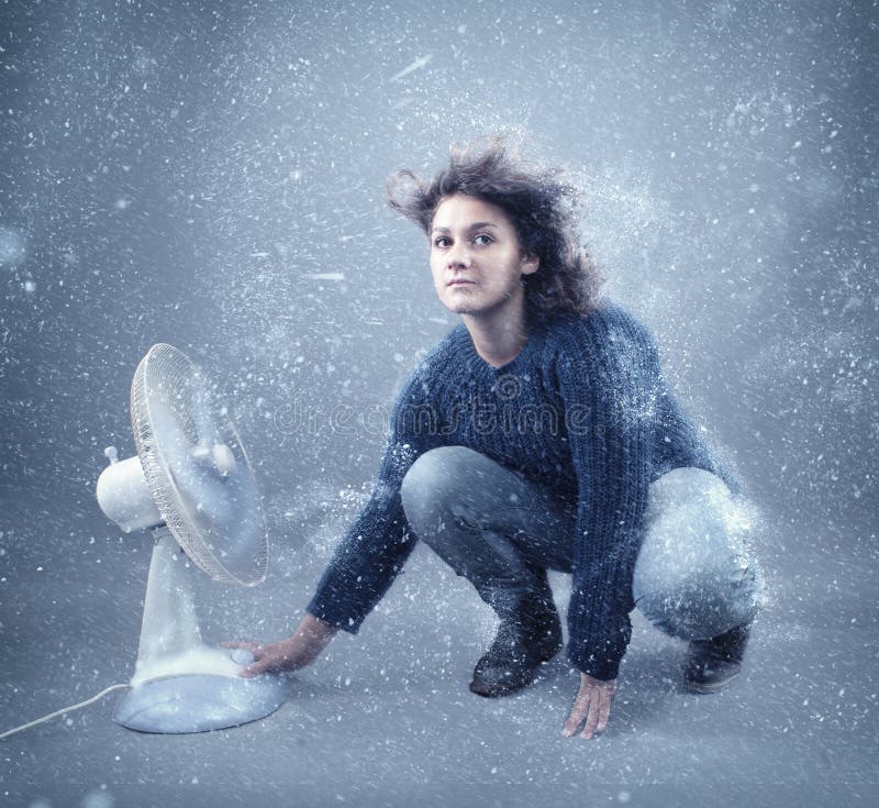Ragazza congelata accanto ad un fan potente fotografie stock libere da diritti Ragazza congelata accanto ad un fan potente fotografie stock libere da diritti